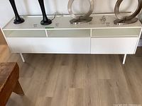 Front view of white IKEA TV console with two drawers and metal legs, placed on wooden floor, showing the overall structure and design.