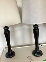 Image showing both black metal table lamps side by side with separate white fabric lamp shades on top.