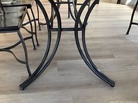 Close-up of the curved black brushed metal base of the dining table highlighting the arch design and sturdy construction
