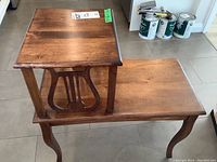 Wood tiered vintage side table with two levels, lyre-shaped side decoration, curved legs, medium brown wood finish. Shows slight wear.