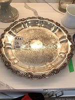 Silver plate tray with ornate shell and scroll edge, detailed engraving visible on tray surface