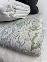 Close-up of quilt fabric with soft pastel floral pattern and folded white cotton textile.