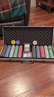 Aluminum case open showing multiple rows of poker chips and dealer/button chips on foam padding