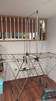 Drying rack fully extended indoors showing its structure with multiple drying bars and foldable metal legs.