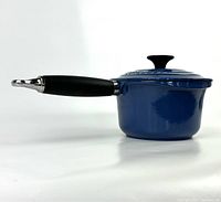 Side view of vintage blue Le Creuset saucepan with attached phenolic handle and lid on top.