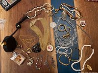 Overview of assorted custom jewelry including necklaces, bracelets, pendants, and decorative item on table