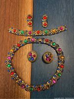 Full jewelry set including necklace, bracelet, and two pairs of earrings displayed on two-tone background.