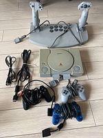 Full set showing PlayStation 1 console with three controllers, dual joystick set, and cables.