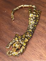 Top down view of articulated jaguar brooch showing full length and gold-tone metal with spots detailing