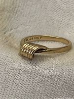 Close-up photo showing side angle of yellow gold ring with twisted loop design and 'DASON 10K' inscription inside band.