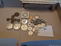 Overview of all coins in the lot laid out in a cardboard box showing various sizes and conditions.