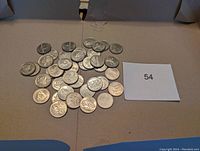 Collection of approximately 37 Canadian millennium quarters laid out on a beige surface next to lot number 54.