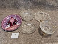 Five dishes arranged on carpet including clear crystal and decorative Santa plate