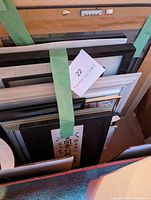 Top view showing the ten pieces of framed art stacked vertically and secured with a green strap.