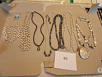 Full lot laid out showing seven pearl jewelry pieces including earrings and six necklaces of varying pearl colors and shapes, plus one with a large pendant.
