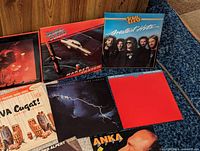 Close up of eight vinyl records including April Wine Greatest Hits, April Wine Harder…Faster, Dire Straits Making Movies, Bob Alpert album, Viva Cugat! percussion album, and others showing cover condition.