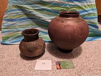 Front view of two raku pottery vases with a business card and lot number 51 in front, showing size and color contrast.