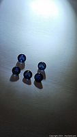 Five deep royal blue round cabochon sapphires arranged on a plain white surface, showing their shape and color under spot lighting.