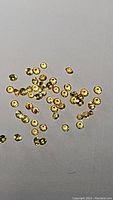 Photo showing multiple small round lemon yellow Ceylon sapphires with diamond cut facets spread on a light surface.