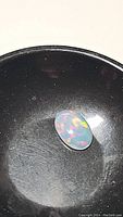 Oval cabochon 1.75ct Ethiopian opal with galaxy pattern and vibrant multicolor play of color against a dark backdrop.