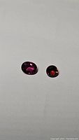 Two garnet gemstones placed on a white background showing the size and color difference.