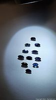 Ten marquis cut natural royal blue sapphires arranged together under focused lighting showing cut shape and color.