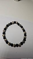 Photo of the stretchy gemstone bracelet showing alternating Dalmatian Jasper and matte black Onyx beads on a white background.