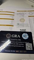 Photo of GRA branded certificate card showing warranty ID and authenticity details for the moissanite gemstone.