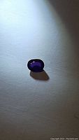 Loose oval faceted purple sapphire on white background
