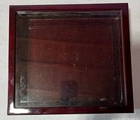Top-down view of the closed display case showing polished dark wood frame and clear glass lid with some minor surface dust.