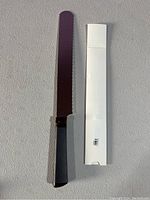 Photo of the bread cutting utensil alongside its white packaging box labeled USA.