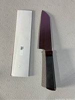 Photo of the kitchen cutting utensil outside its white box on a light-colored surface.