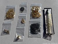 Overview photo showing all necklaces, earrings in small plastic bags, and jewelry tool in packaging on a textured surface.