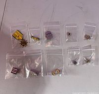 Photo of 10 vintage military pins and medals individually bagged on a flat surface revealing various designs and colors.