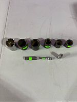 Nine chrome sockets of varying sizes arranged in a row, showing deep and shallow types with green size stickers visible on most.