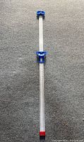 Full length image of the V belt measuring tool showing the graduated ruler with blue sliding head and end.