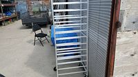 Full view of the tall aluminum baker's rack showing all 12 slots for cookie sheets and wheels.