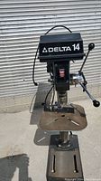 Front view of Delta 14 bench drill press showing head unit, adjustable table, and base.
