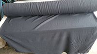Full view of black fabric rolled out showing width and texture