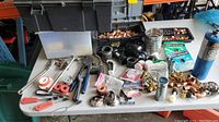 Overview of workbench with assorted hand tools, fittings, Teflon tape and sink parts