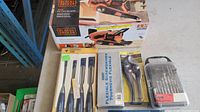 Photo showing Black & Decker belt sander box, wood chisel set, flexible screwdriver box, pipe cutter, and drill bit set.