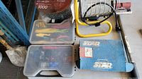 Overview of the lot including tools, two plastic cases with assorted items, yellow work light, and tote