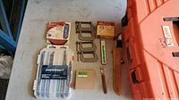 Overview of the lot on a table showing C-clamps, saw blades, Diablo fiber discs package, fish filet cutter knife in leather sheath, glass cutters, and the orange Homer Box toolbox.