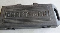 Closed molded black plastic carrying case branded Craftsman to protect and carry the reciprocating saw.