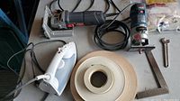 Overview of lot showing biscuit joiner, palm router, steam iron, edge banding roll, bag of biscuits and wrench