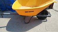 Side view showing yellow plastic bucket with True Temper logo and steel frame.
