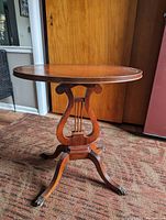 Front view of 19th century mahogany lyre side table with round leather top and lyre-shaped stretcher.