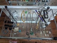 Photo showing costume jewelry items including watches, necklaces, bracelets, and earrings on a glass top table.