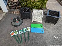 Three square plastic garden planters - two black and one white; plastic Christmas tree stand; five vintage vegetable identification stakes; two foam knee pads