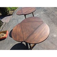 Pair of cloverleaf-shaped wooden side tables outdoors showing the open tops with three drop leaves extended.
